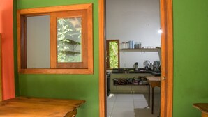Eine Küche mit einer grünen Wand, einem Holztisch und einem Fenster mit Blick auf Grünflächen.