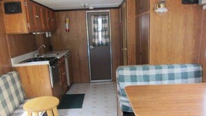 Un intérieur de camping-car compact comprenant un coin cuisine, un espace repas et un coin nuit.