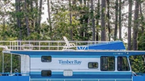 A boat named 'Timber Bay' with a blue and white color scheme, a covered deck area, and a cabin with windows. - The Mallard Houseboat at Timber Bay (Babbitt)