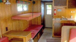 A compact RV interior with a bunk bed, kitchenette, and a small dining area. - The Turtle Houseboat at at Timber Bay (Babbitt)