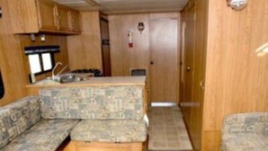 Ein kompaktes Wohnmobil-Interieur mit einer Küchenzeile, einer Sitzecke und einer Tür zu einem Flur.