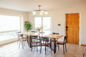 Un espace repas comprenant une table et des chaises en bois, un luminaire au plafond et une porte.