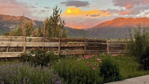 A wooden fence, a concrete path, and a mountainous landscape with a sunset.