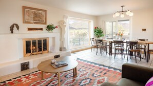 A living room with a fireplace, dining area, and large windows with mountain views.