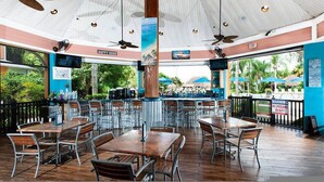 A restaurant with multiple tables and chairs, a bar area, and a view of the beach. - Go 13 - Bahama BAY in Davenport (Davenport)