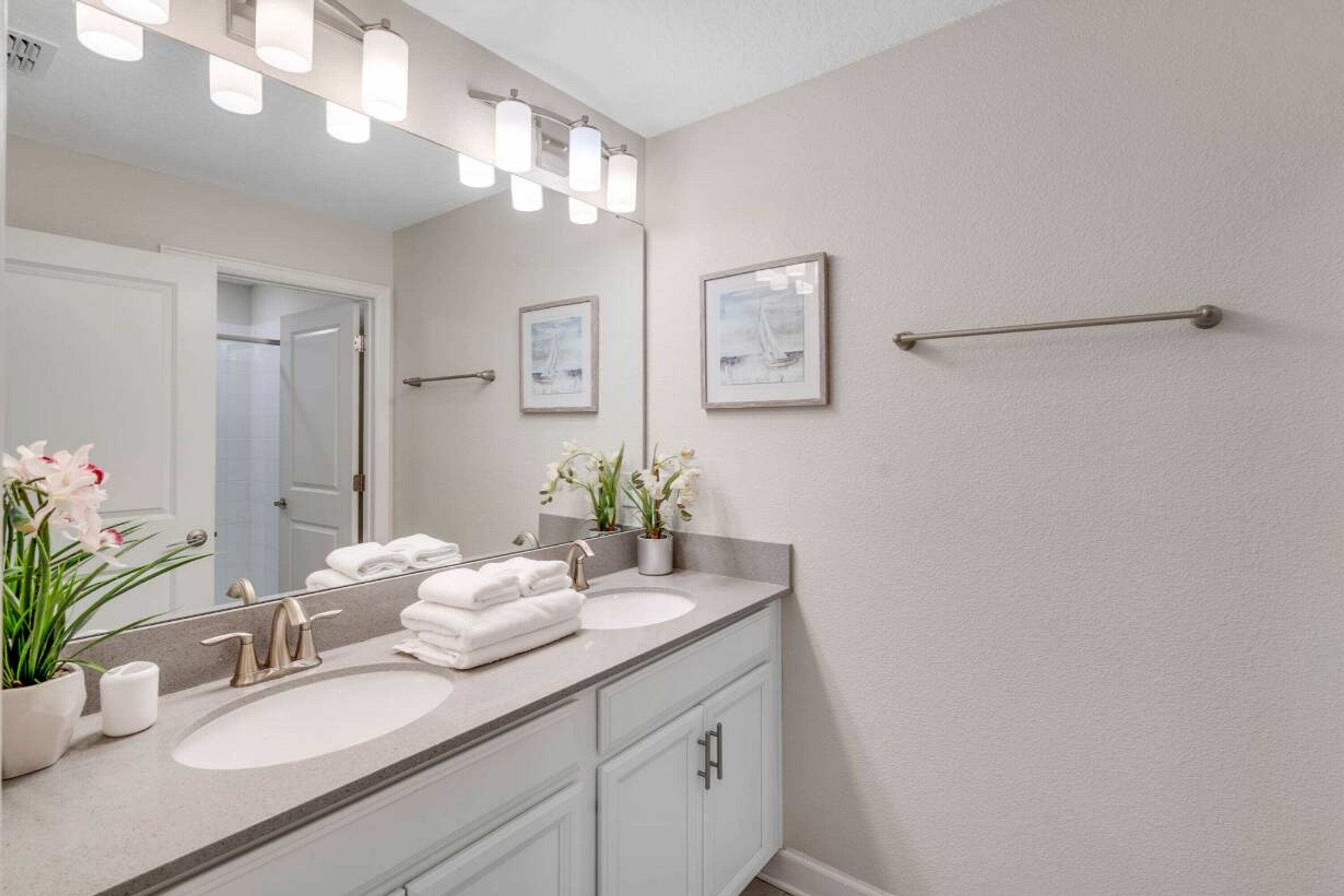 A bathroom with a double sink, a large mirror, and a towel rack.