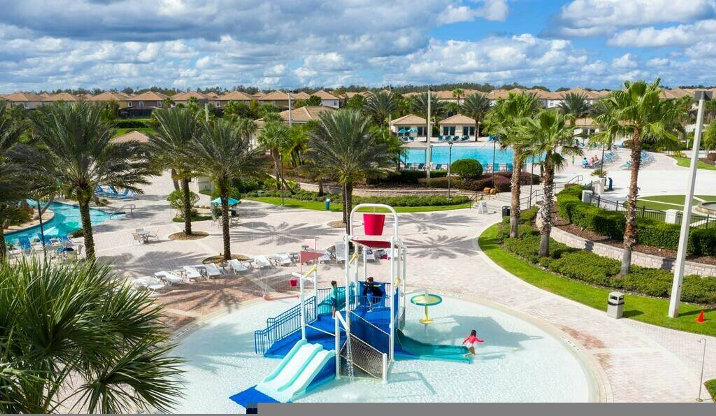 Ein Wasserpark mit Rutschen und Schwimmbecken, umgeben von Palmen und einer Wohngegend.