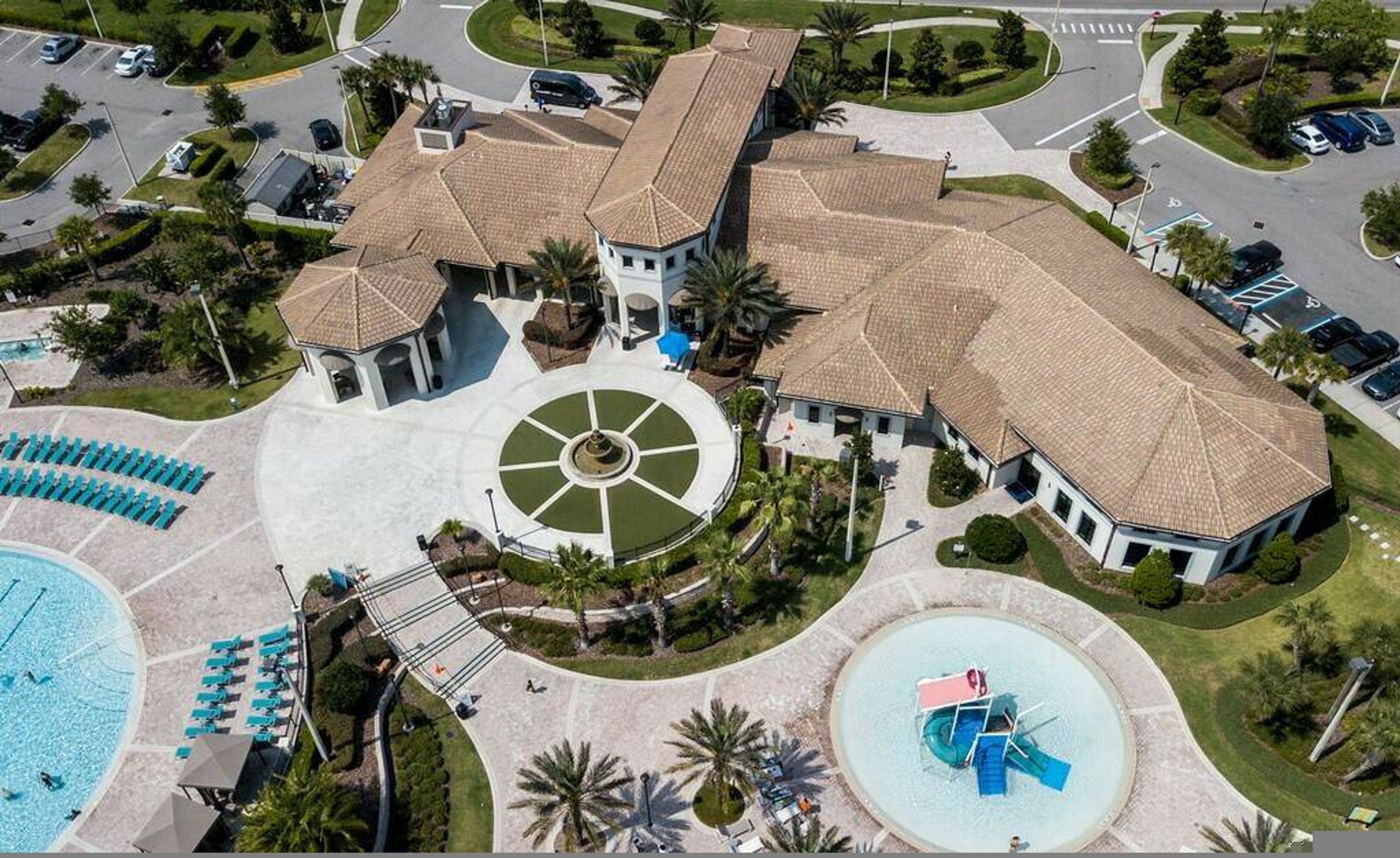 Un grande resort con diverse piscine, un cortile centrale e un'area parcheggio.