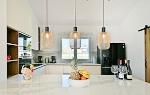 A modern kitchen with a marble countertop, a fruit bowl, wine glasses, and a black refrigerator. - Awesome home in Porec (Porec)