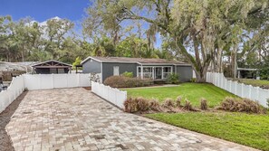 A residential property with a paved driveway, a fenced yard, and a house with a porch. - Private Pool, Games, Firepit Ultimate Tampa Fun House (Tampa)