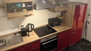 Kompakti keittiö, jossa on kaasuliesi, sisäänrakennettu uuni, leivänpaahdin ja puiset kaapit.