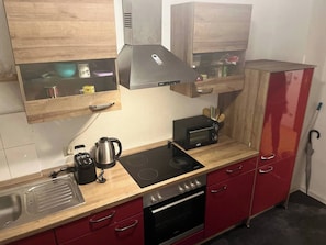 Uma cozinha compacta com fogão, forno, micro-ondas e chaleira no balcão.