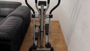 Huoneessa on puulattia ja musta nahkasohva, ja siellä seisoo paikallaan oleva kuntopyörä.