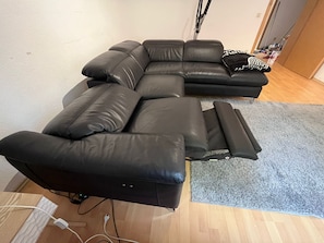 Ein modulares Sofa mit Liegefunktion, ein grauer Teppich und ein Holzboden.