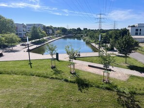 A park with a pond, walking paths, and modern buildings in the background.