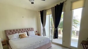 A bedroom with a large bed, a ceiling fan, and a view of the outdoors through a sliding door. - Cozy House in Selvanova 3B (Playa del Carmen)