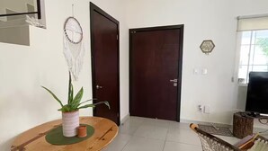 A room with a wooden table, a potted plant, a dreamcatcher, and a television. - Cozy House in Selvanova 3B (Playa del Carmen)
