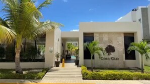 A modern building with a sign reading 'Casa Club,' surrounded by palm trees and a paved walkway. - Cozy House in Selvanova 3B (Playa del Carmen)