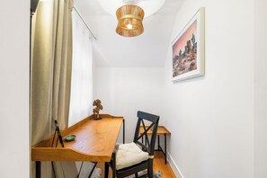 Une pièce comprenant une table en bois, une chaise, un luminaire suspendu et un tableau encadré accroché au mur.