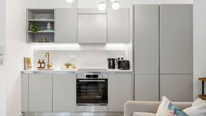 A modern kitchen with a built-in oven, a sink, and a countertop with kitchen appliances. - Stylish Seaside Apartment | Minutes from Beach (Eastbourne)