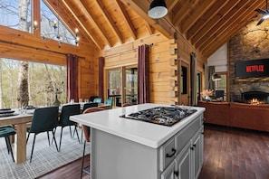 A cabin interior with a kitchen, dining area, and fireplace. - Best of Blue Ridge | Hot Tub |  Games | Pickleball (Blue Ridge)