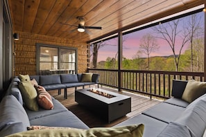 A covered outdoor seating area with a fire pit, wooden deck, and a view of trees and hills. - Best of Blue Ridge | Hot Tub |  Games | Pickleball (Blue Ridge)