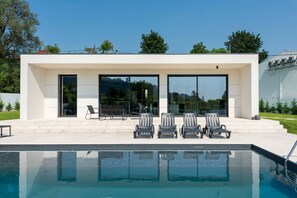 A modern house with a swimming pool, outdoor seating, and large windows. - 202 - Casinha da Ribeira (Vila Verde)