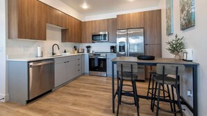 A modern kitchen with wooden cabinets, stainless steel appliances, a microwave, and a refrigerator. - Two-bedroom Flat at Teton Peaks (Driggs)