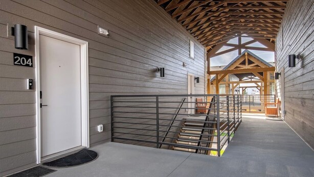 A covered hallway with a metal gate, wooden beams, and a door marked with the number 204. - Two-bedroom Flat at Teton Peaks (Driggs)