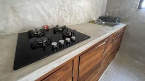 Een keuken met een zwart fornuis, houten kastjes en een marmeren aanrecht.