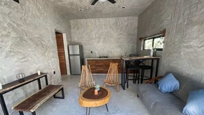 Een modern interieur met een bank, een ronde houten tafel, een bankje en een eethoek met stoelen.