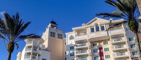 A multi-story hotel with balconies, a central tower, and palm trees.