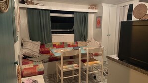 A compact living space with a sofa, a small table, a TV, and a window with curtains.