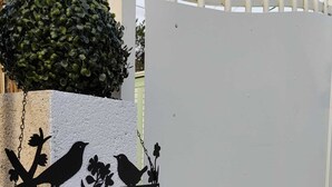 A black and white 'Bienvenue' sign with bird silhouettes on a white wall.