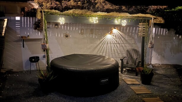 A circular outdoor seating area with a black cushion, a chair, and a small table.