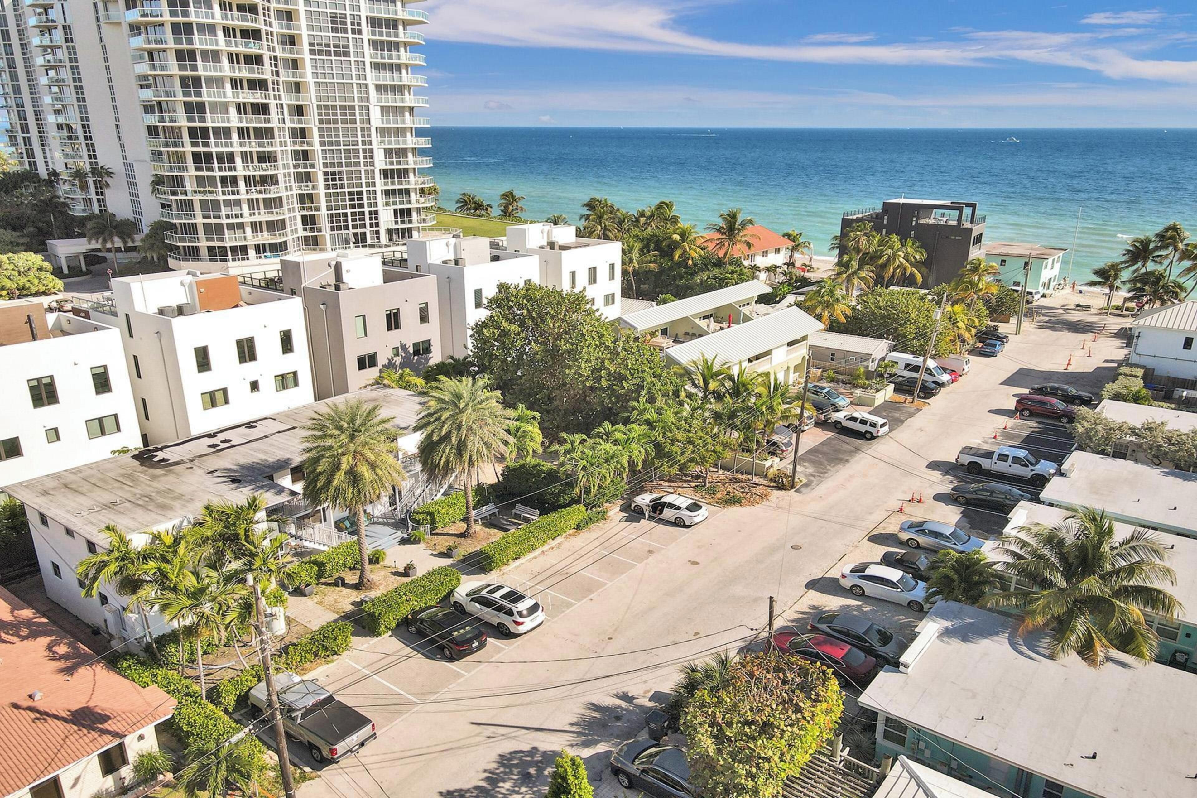 An aerial view of a coastal urban area with buildings, parking, and a view of the ocean.