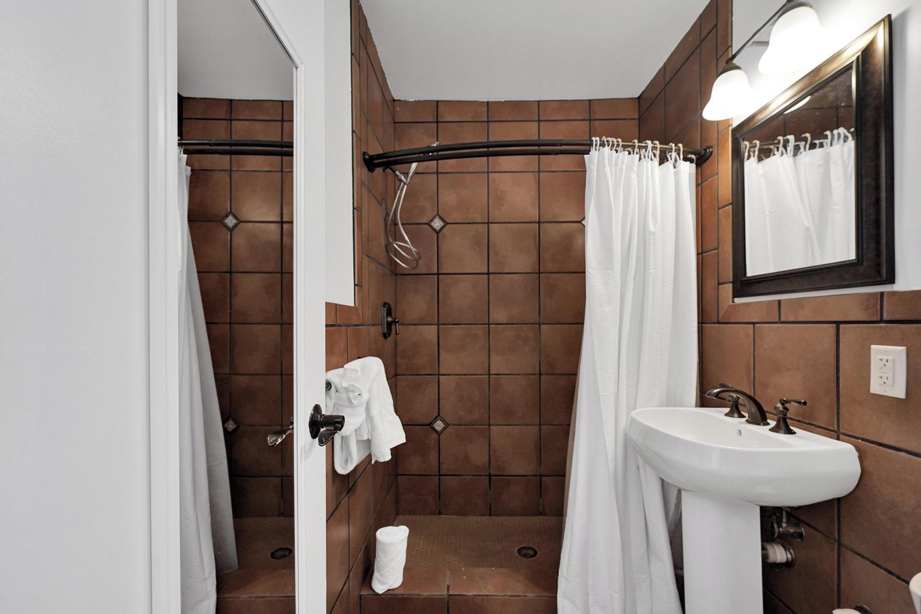 A bathroom with a shower, a sink, and a mirror.