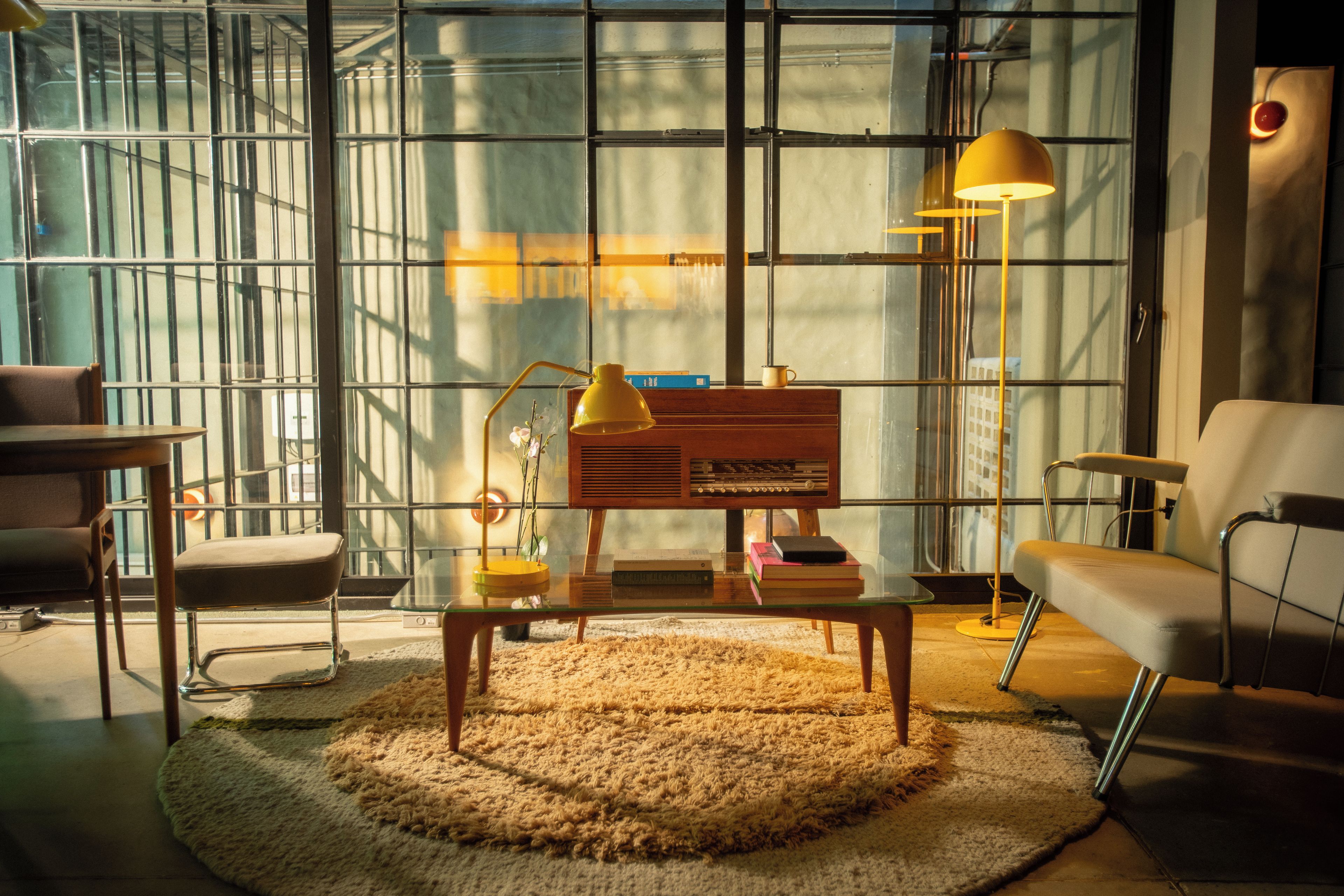 A modern living room with a glass wall, a wooden coffee table, and contemporary furniture.