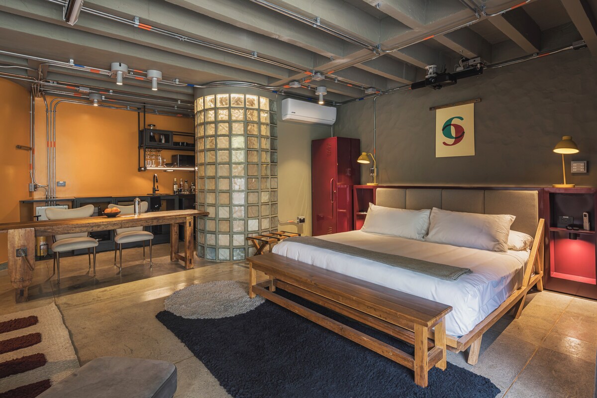 Un dormitorio moderno con una cama grande, un escritorio y una estructura cilíndrica de vidrio singular.