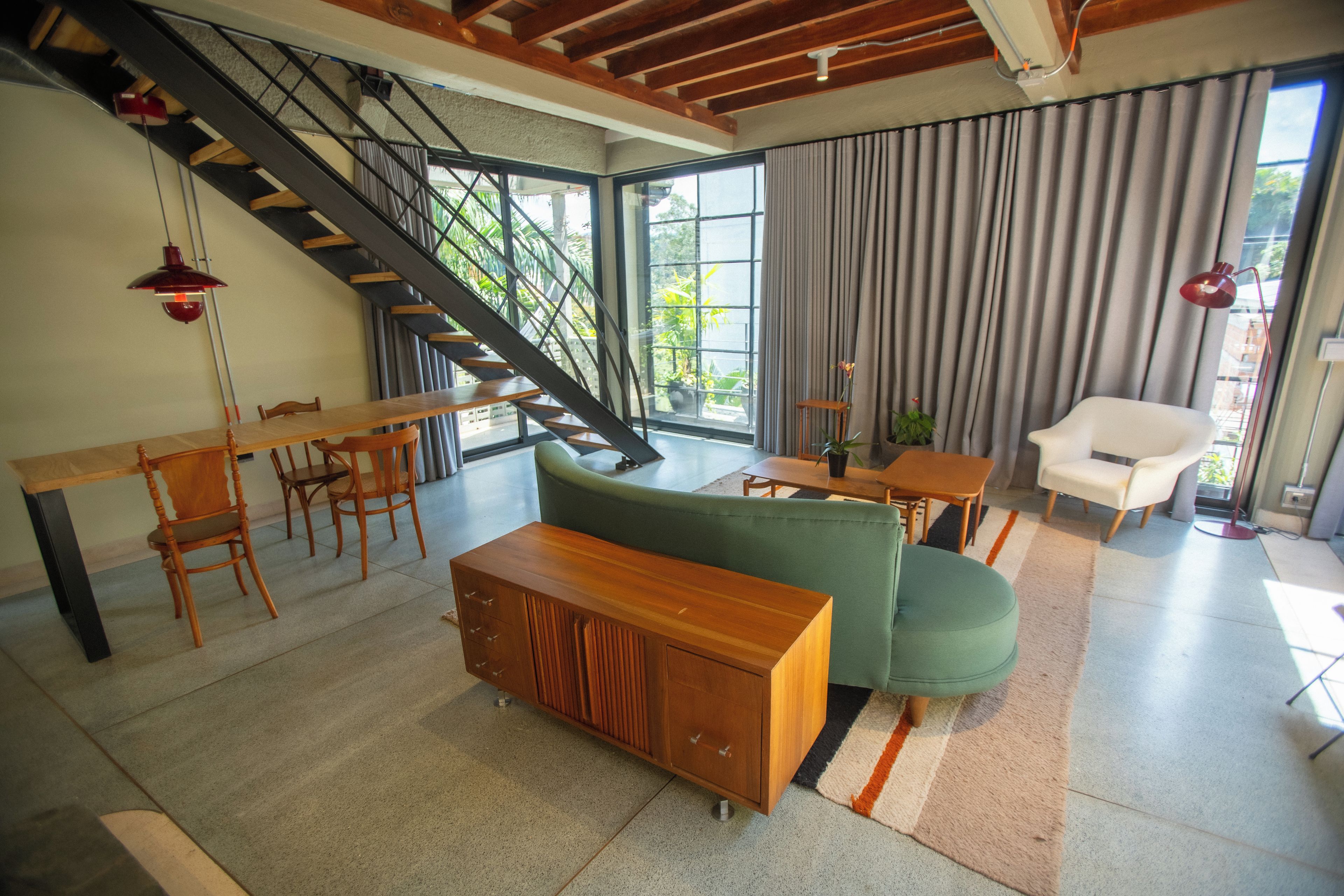 Una sala moderna con una escalera, un sofá, una mesa de comedor y sillas.