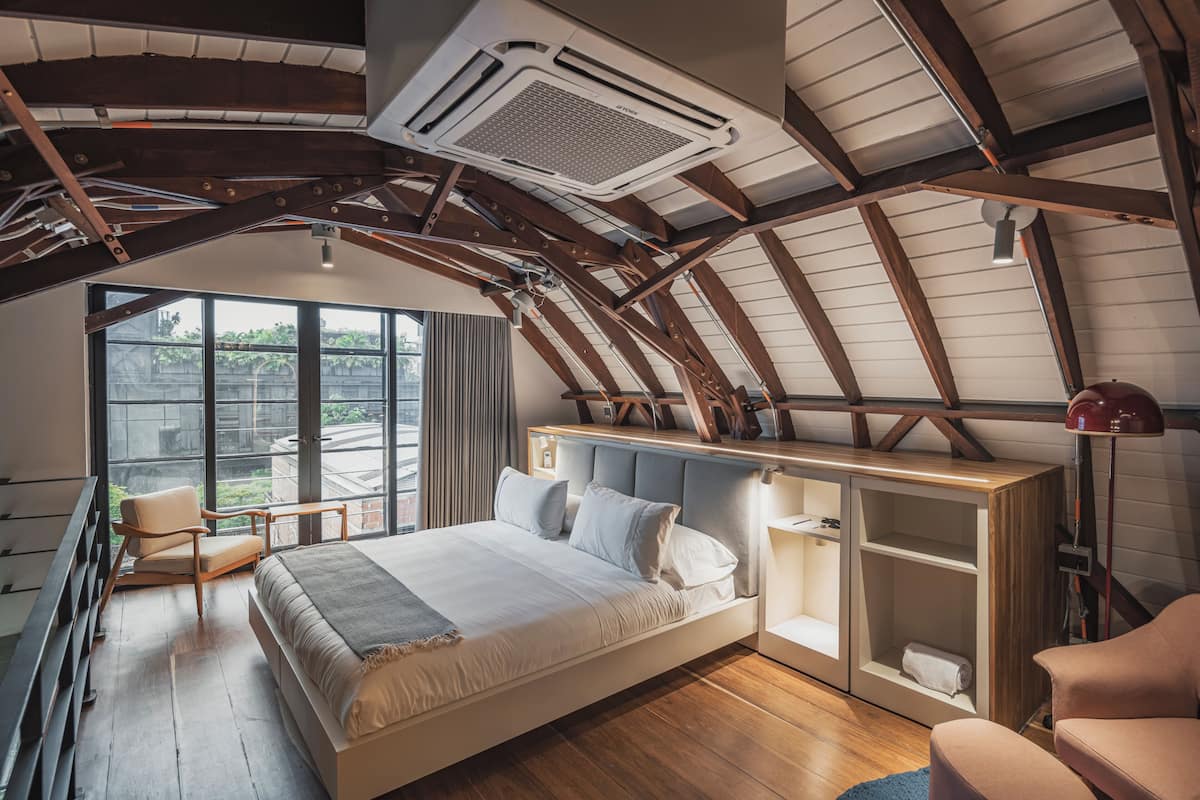 A bedroom with a bed, a chair, a desk, and a large window.