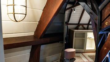 A bathroom with a brass sink, a mirror, and a hanging light fixture.