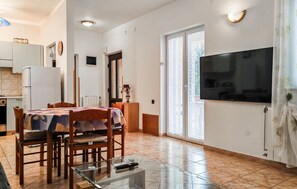 Ein modernes Apartment mit Essbereich, Küche und großem Fernseher.