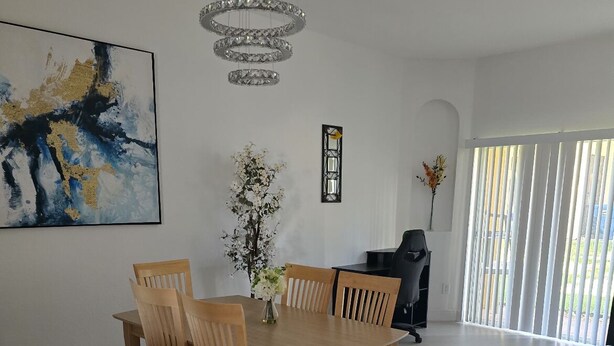 A dining area with a wooden table and chairs, a chandelier, and a large abstract painting on the wall. - 130 Napoli Dr, Davenport - Regal Palms Resort (Davenport)