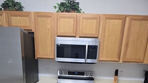 A kitchen with wooden cabinets, a stainless steel refrigerator, a microwave, and an oven. - 130 Napoli Dr, Davenport - Regal Palms Resort (Davenport)