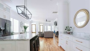 A modern kitchen with white cabinetry, a marble countertop, and a black pendant light. - Stunning Downtown 3BD-2.5BA Home| Near Forsyth Pk (Savannah)