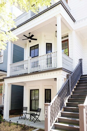 Ein zweistöckiges Haus mit Balkon, Treppe und Garagentor.