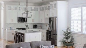 A modern kitchen with white cabinetry, stainless steel appliances, and a central island. - Stunning Downtown 3BD-2.5BA Home| Near Forsyth Pk (Savannah)