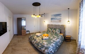 Ein Schlafzimmer mit Bett, Nachttisch, Wandfernseher und einem Gemälde.