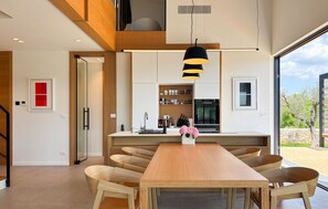 Eine moderne Küche mit einer zentralen Kochinsel, Holzstühlen und Pendelleuchten.